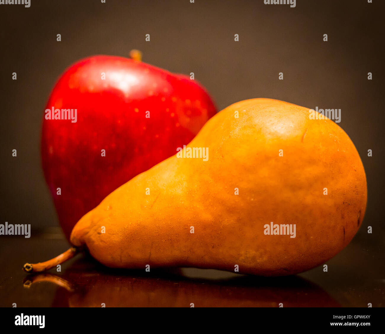 Einen leckeren roten Apfel und eine braune Birne auf einem schwarzen Hintergrund mit einem weichen Textur und Vignette. Stockfoto