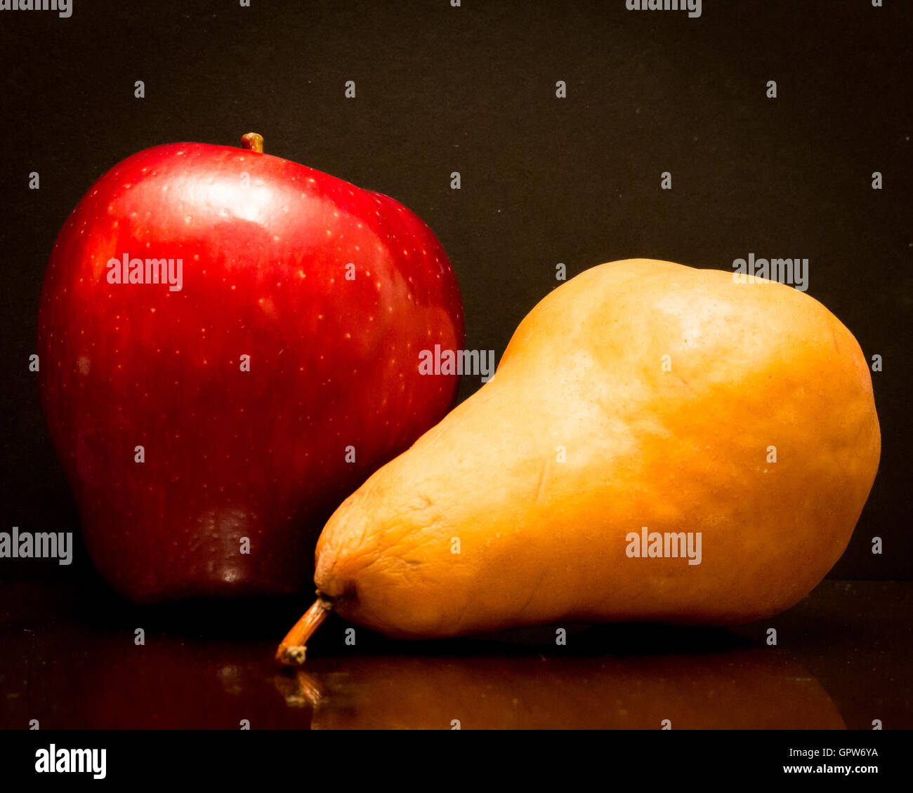 Einen leckeren roten Apfel und eine braune Bosc Birne auf einem schwarzen Hintergrund. Stockfoto