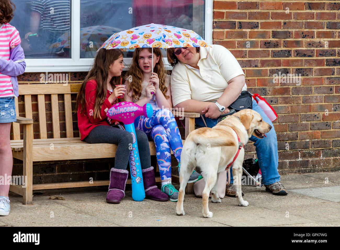 Eine Familie Unterstände aus der Regen während der jährlichen Hartfield Dorffest, Hartfield, East Sussex, UK Stockfoto