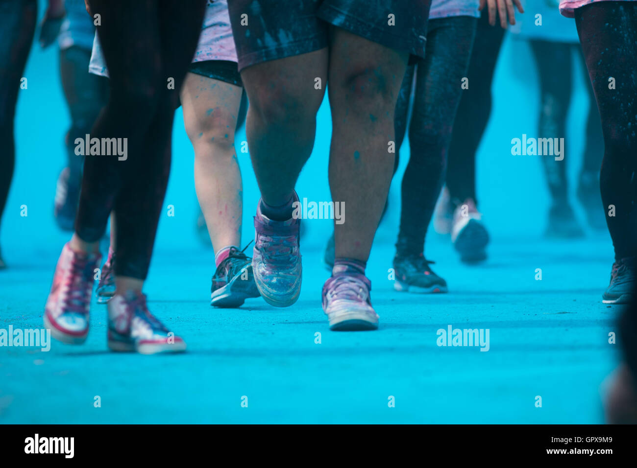 Menschen die Teilnahme an der Farbe Run - Runners Beine inmitten von blauen Pulver Stockfoto