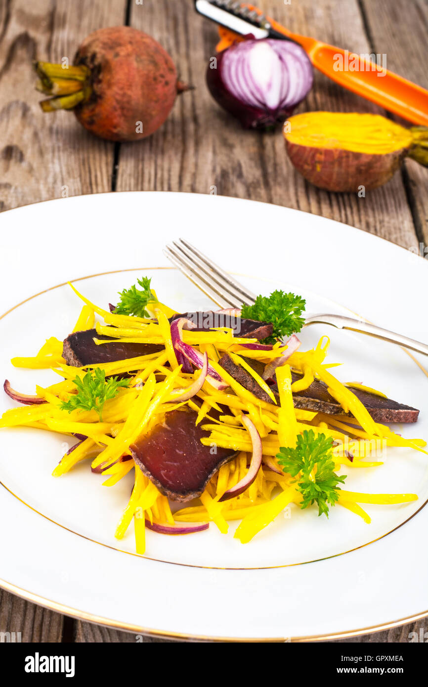 Salat von gelben Rüben mit roten Zwiebeln und Dörrfleisch Stockfoto