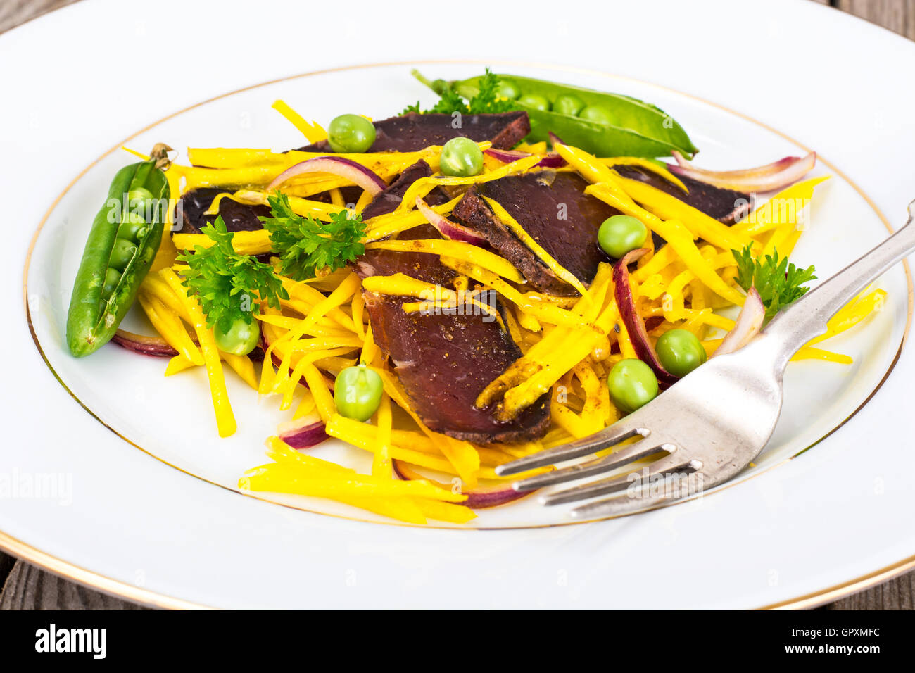 Salat von gelben Rüben mit roten Zwiebeln und Dörrfleisch Stockfoto