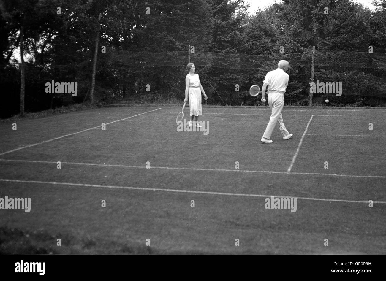 1930er Jahre, vor Gericht historische, paar auf eine äußere Lawn Tennis spielen, Spreyton Dorf, Devon, England. Stockfoto
