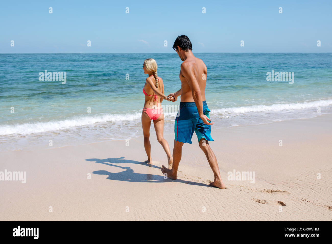 Voller Länge Schuss junges Paar geht für Schwimmen im Meer. Frau an Hand von ihrem Freund bei einem Spaziergang am Ufer Meeres. Staatsstreich Stockfoto