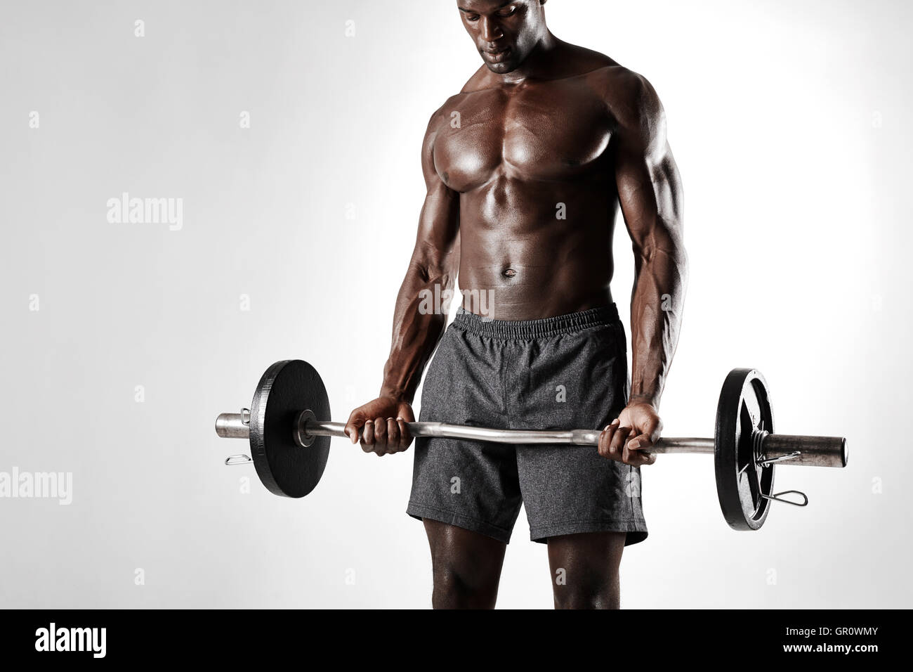 Studioaufnahme des schwarzen Mannes Heben von Gewichten vor grauem Hintergrund. Afrikanische Sportler trainieren mit Langhantel. Stockfoto