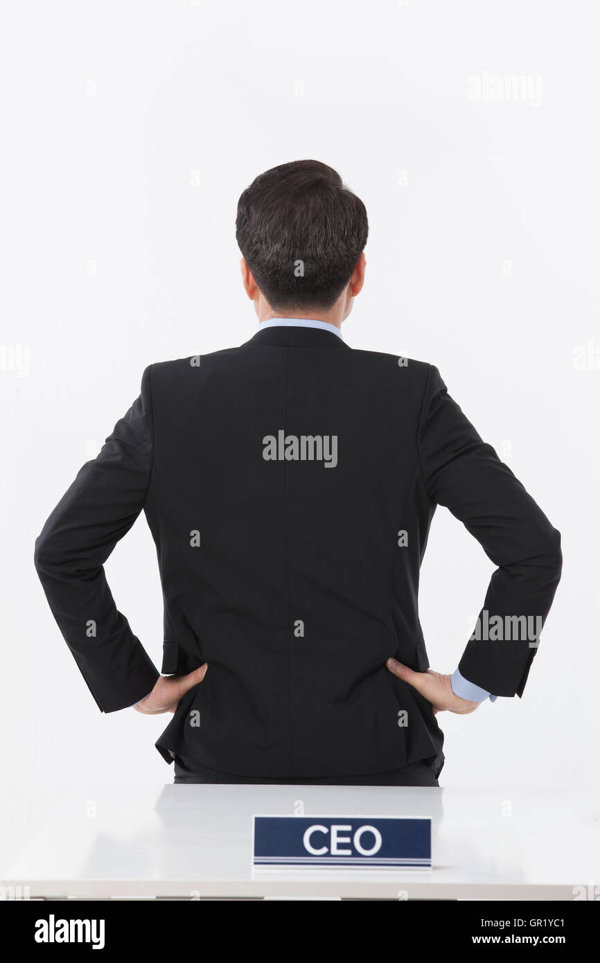 Rückseite des mittleren gealterten CEO mit seinen Händen auf Taille Stockfoto