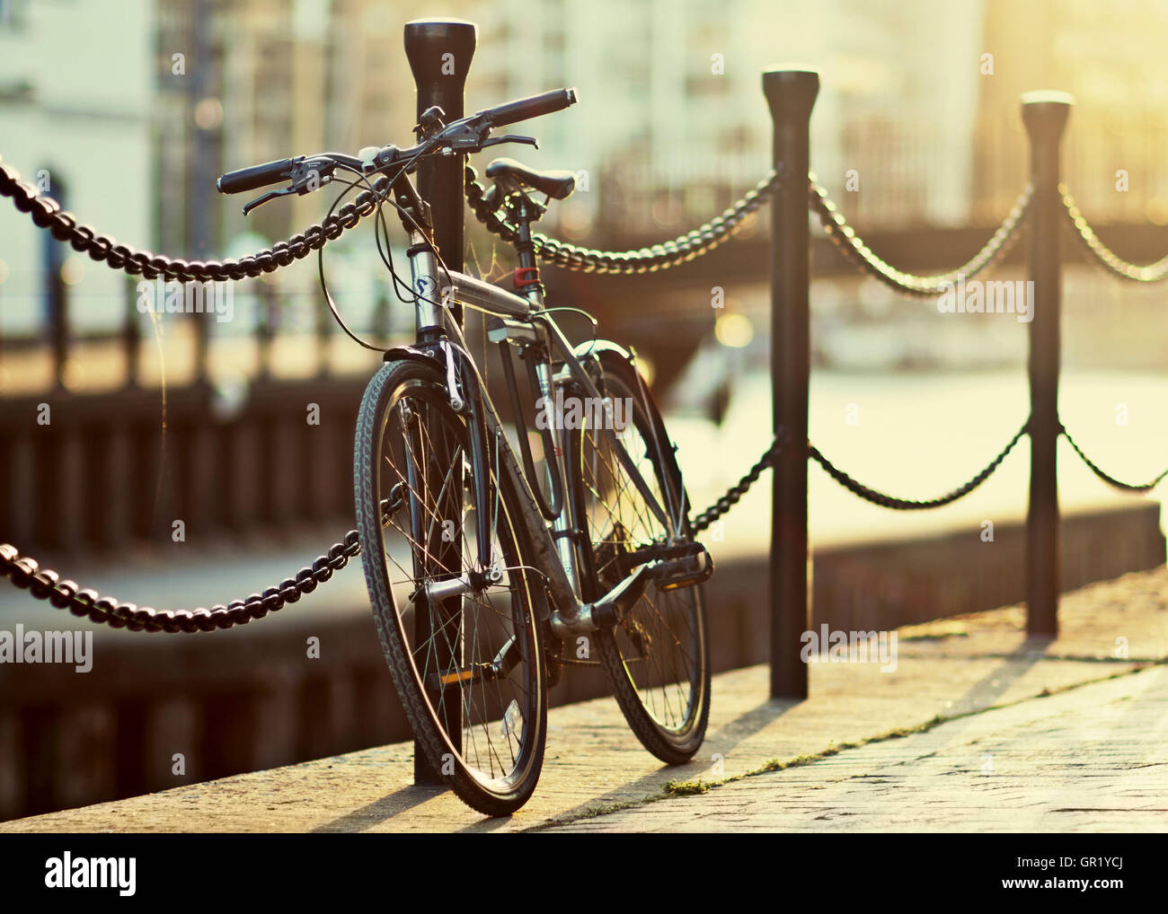 Pendler Fahrrad stehend auf einem Zaun während des Sonnenuntergangs in Limehouse Bassin, East London. Stockfoto