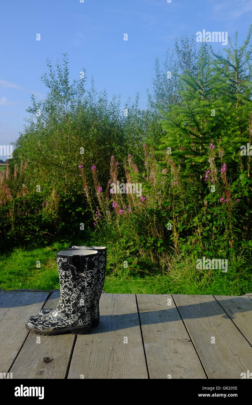 Gemusterte Gummistiefel auf Belag vor Laub Stockfoto