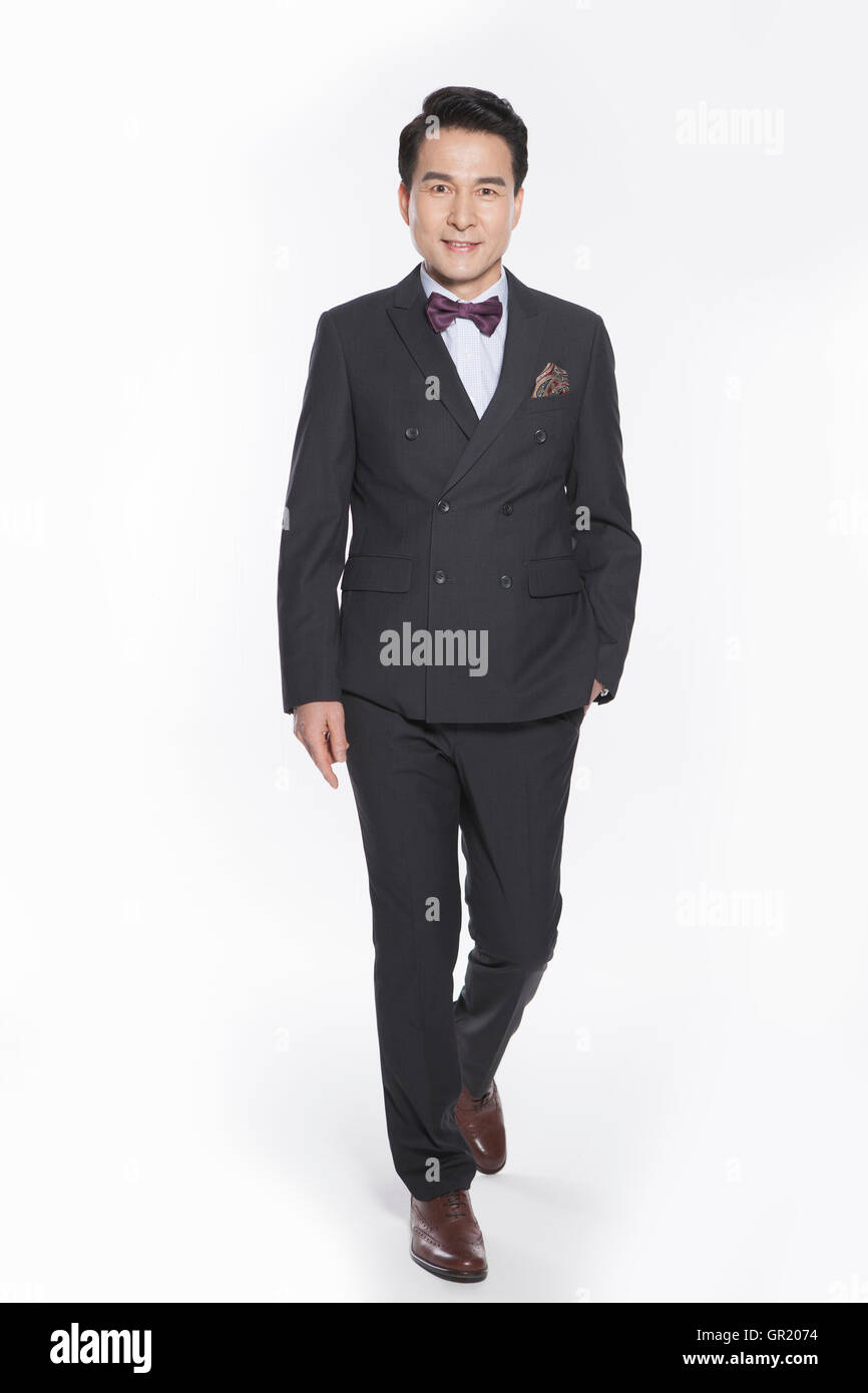 Lächelnd Mitte im Alter Geschäftsmann im Anzug zu Fuß mit einer Hand in der Tasche Stockfoto