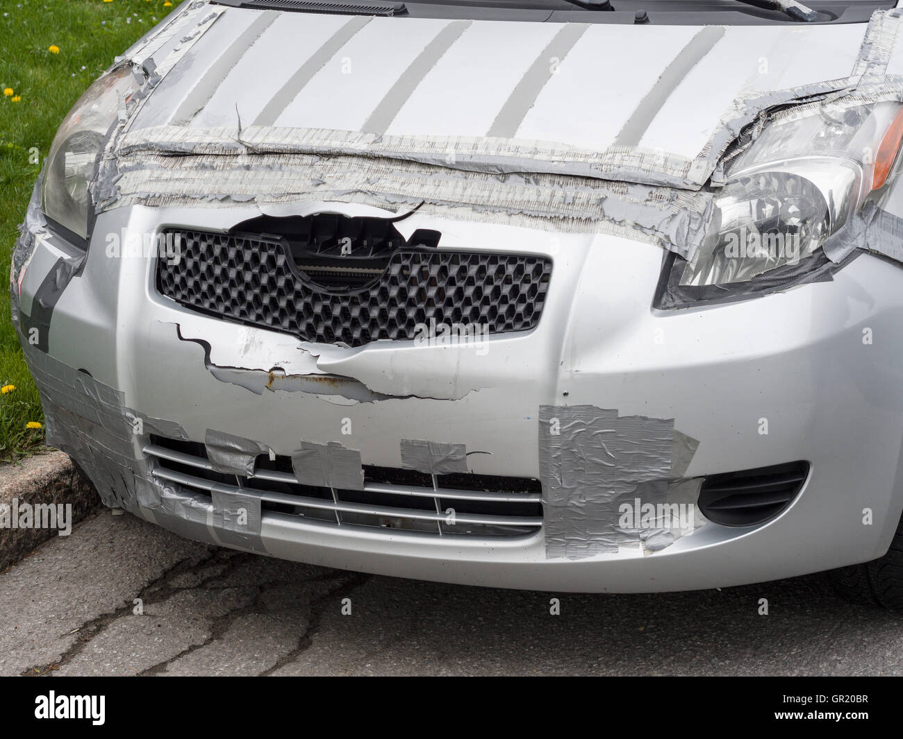 Bandbasierte Autowerkstatt. Einem silbernen Auto ist mit grauem Klebeband geflickt, nach ein Unfall einen Front-End-Schaden verursacht hat. Stockfoto