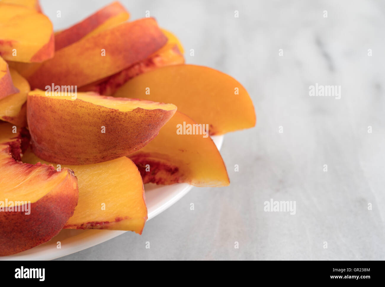 Ein Teller voller Nektarine Scheiben auf einen Marmortisch. Stockfoto