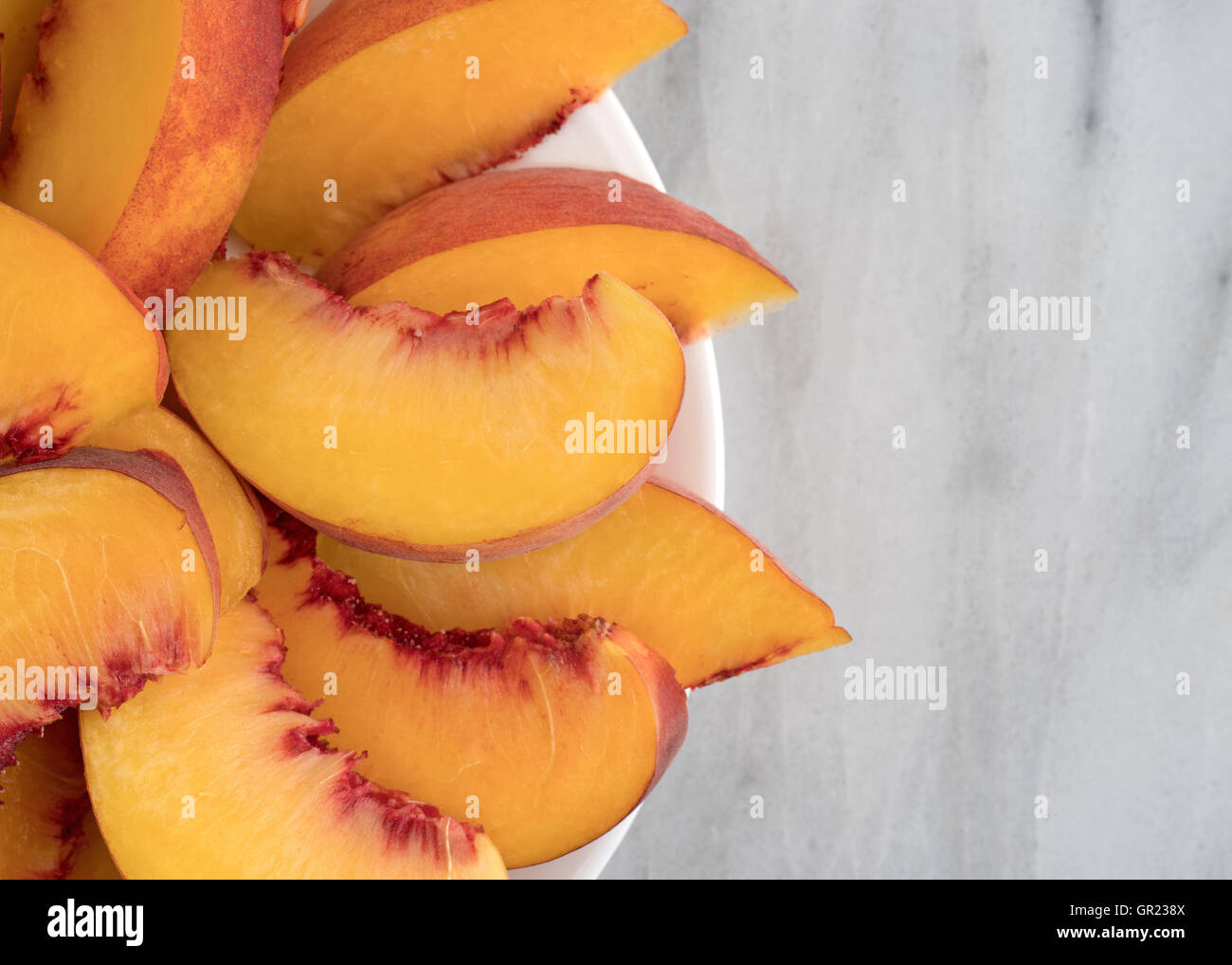 Draufsicht der Nektarine Scheiben auf einem weißen Teller oben auf einen Marmortisch. Stockfoto