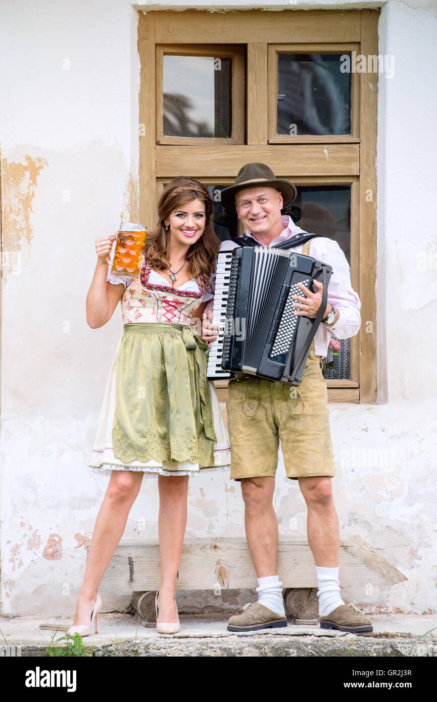 Paar in bayerischer Tracht mit Bier und Akkordeon Stockfoto