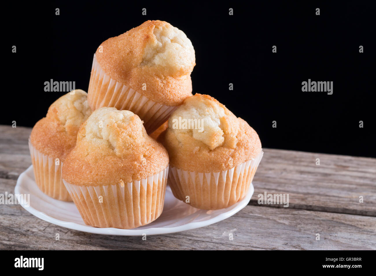 Nahaufnahme von frischen hausgemachten Muffins auf einem Holztisch und schwarzem Hintergrund Stockfoto