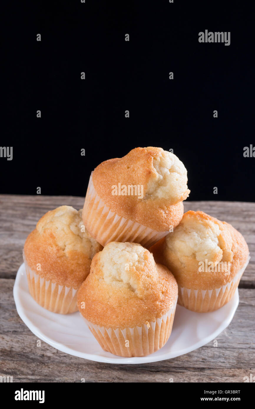 Nahaufnahme von frischen hausgemachten Muffins auf einem Holztisch und schwarzem Hintergrund Stockfoto