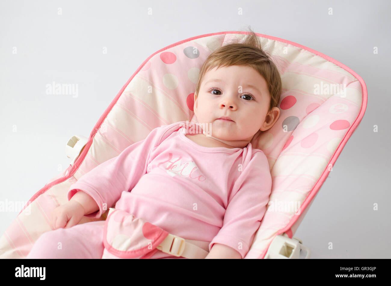 schönes glückliches Babymädchen in einer Wippe tragen rosa Strampelanzug Stockfoto