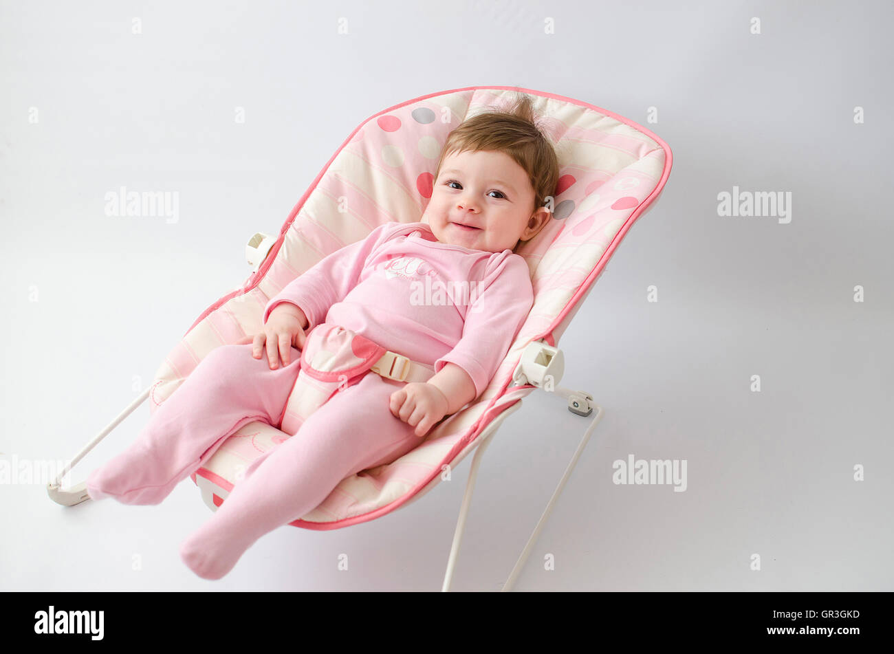 schönes glückliches Babymädchen in einer Wippe tragen rosa Strampelanzug Stockfoto