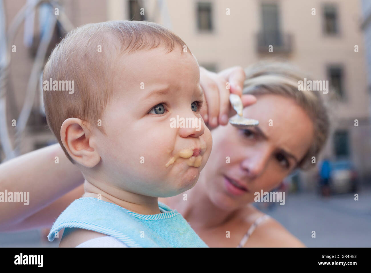 Mutter versucht, ihr Baby Boy mit Obst Brei zu füttern, obwohl er es ablehnt Stockfoto