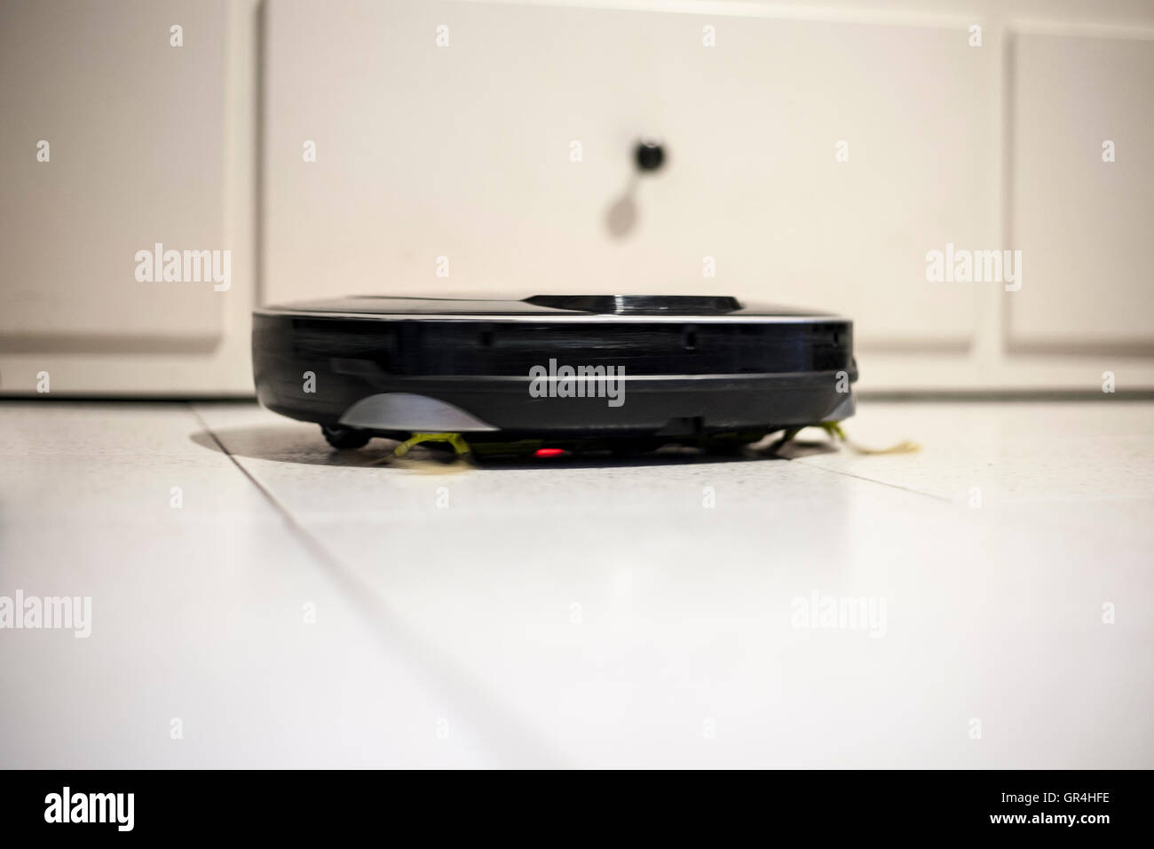 Roboter-Staubsauger auf glasierten Fliesen bei der Arbeit. Zeitlupe erschossen Stockfoto