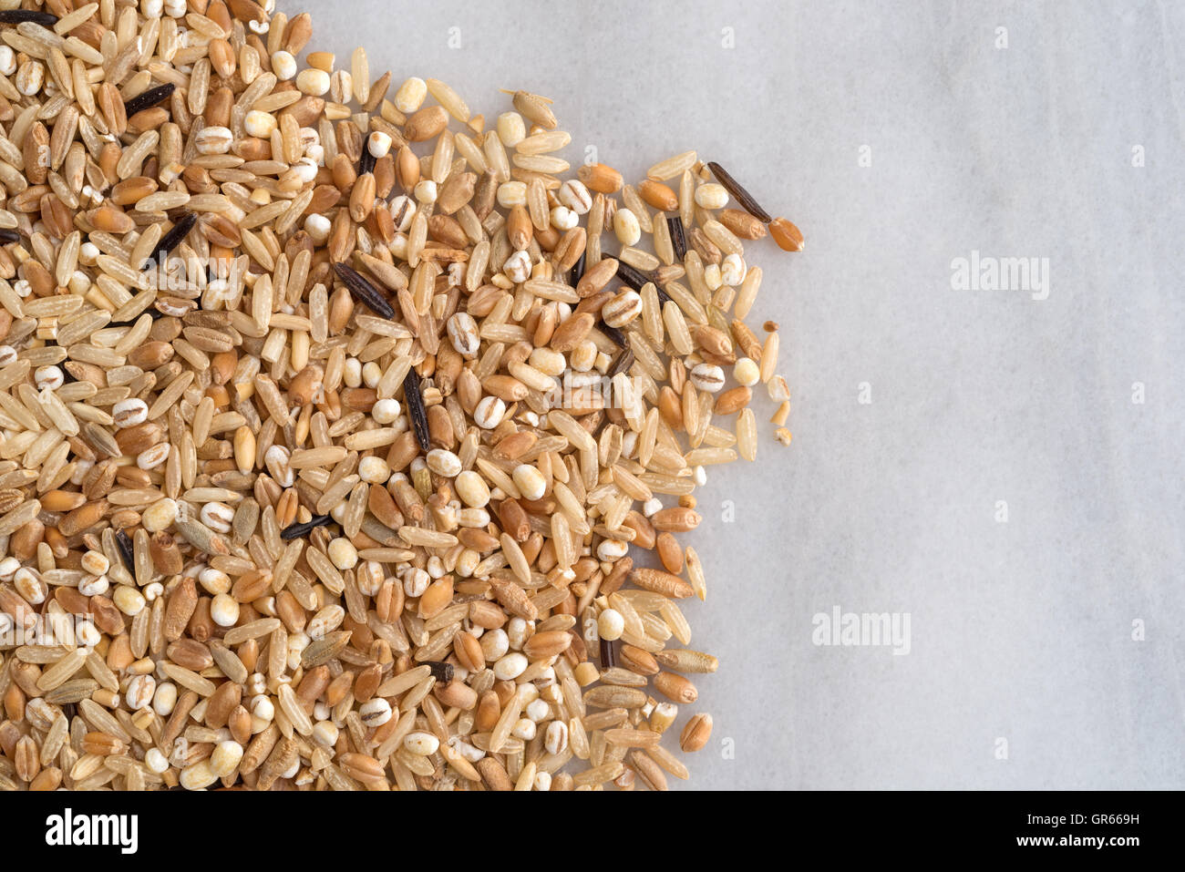Draufsicht auf verschiedene Sorten von Reis und Getreide auf ein Schneidebrett aus Marmor. Stockfoto