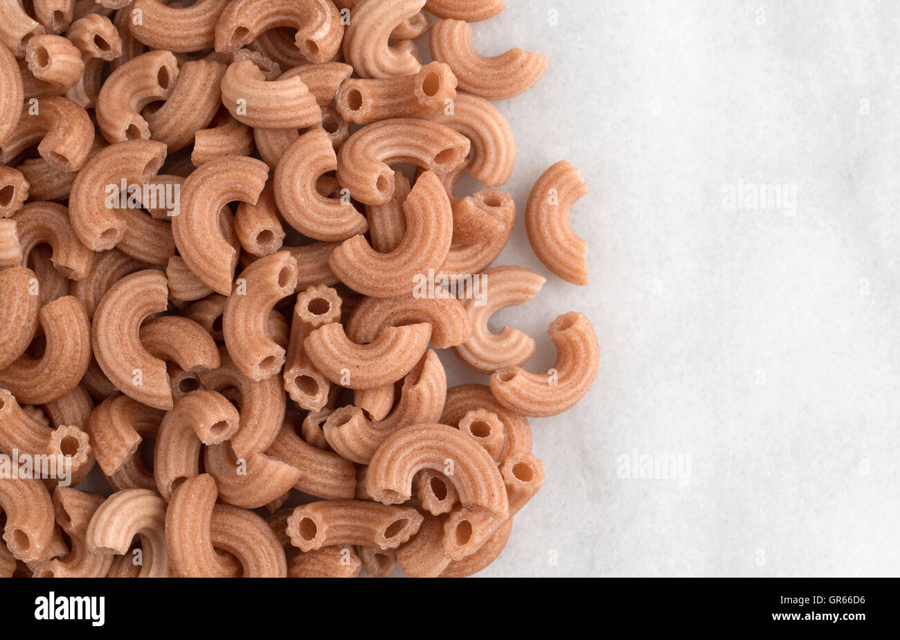 Draufsicht auf rotem Reis Ellenbogen geformten Nudeln auf grauem Marmor Schneidebrett. Stockfoto