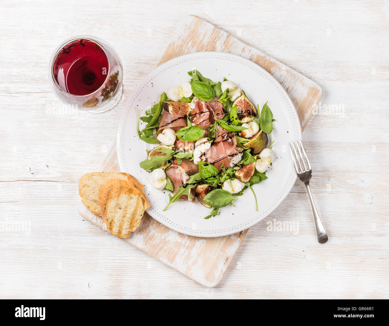 Schinken, Rucola, Feigen-Salat mit Brot und Glas Rotwein Stockfoto