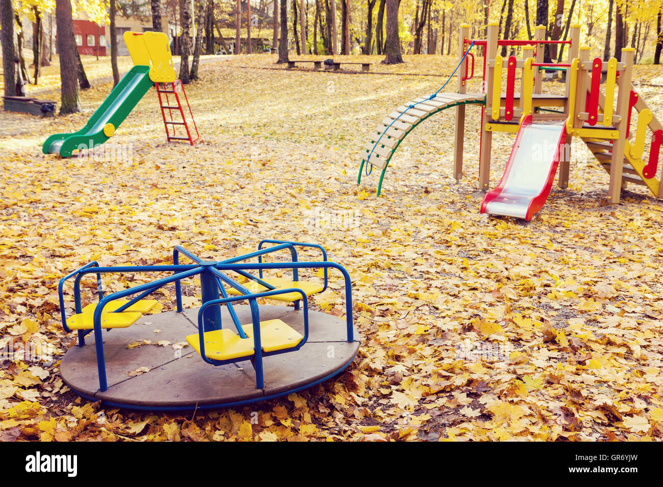 Leere Spielgeräte im Park voller gelber Ahorn Blätter im Herbst Stockfoto