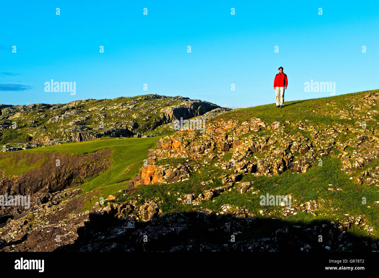 Frau In einer roten Jacke, stehend auf felsigen Wiese, Assynt, Schottland, Großbritannien Stockfoto