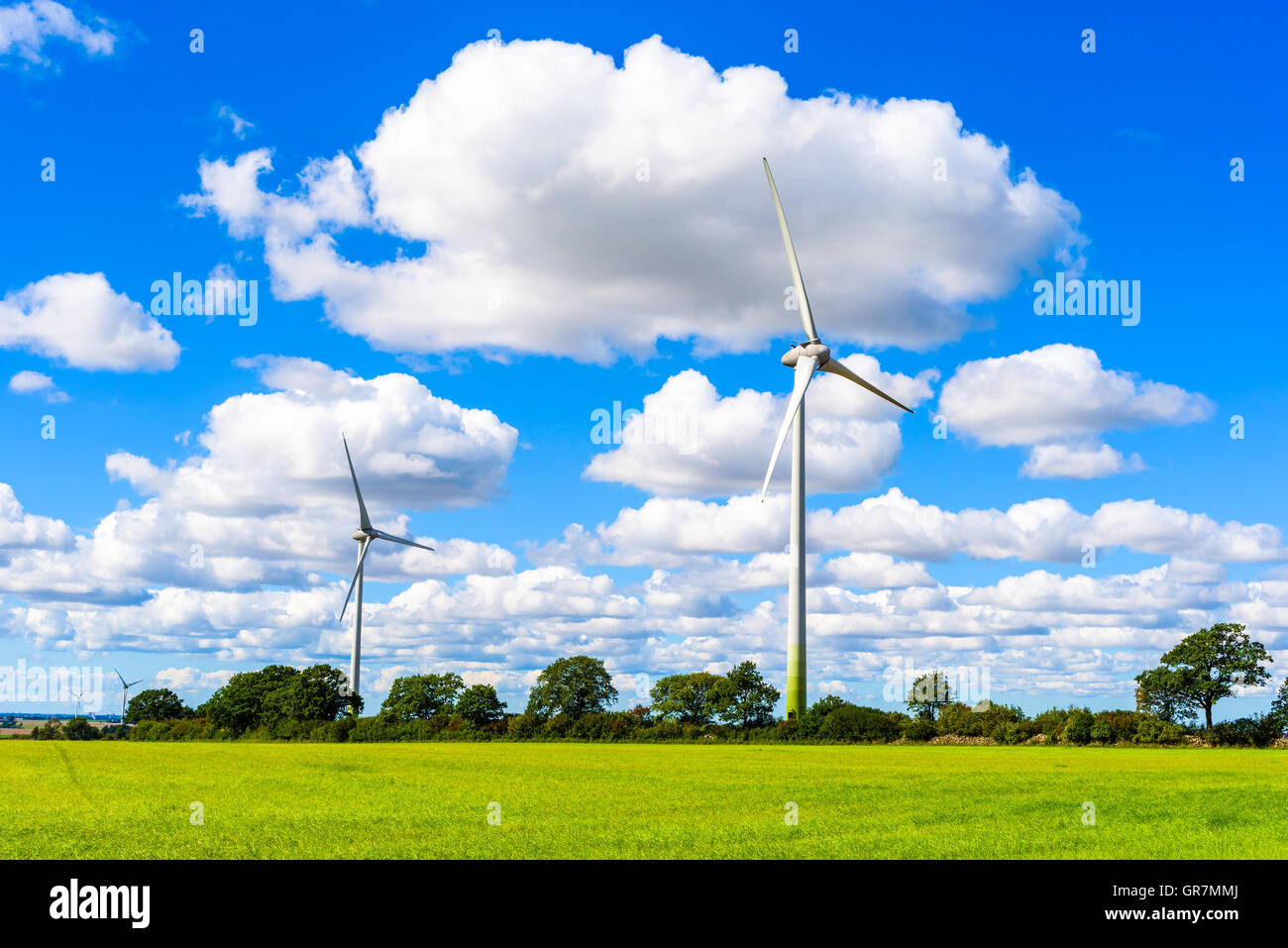 Nachhaltige Energie aus Windkraftanlagen in flachen Ackerland mit feinen Wolken Overhead. Skane in Südschweden. Stockfoto
