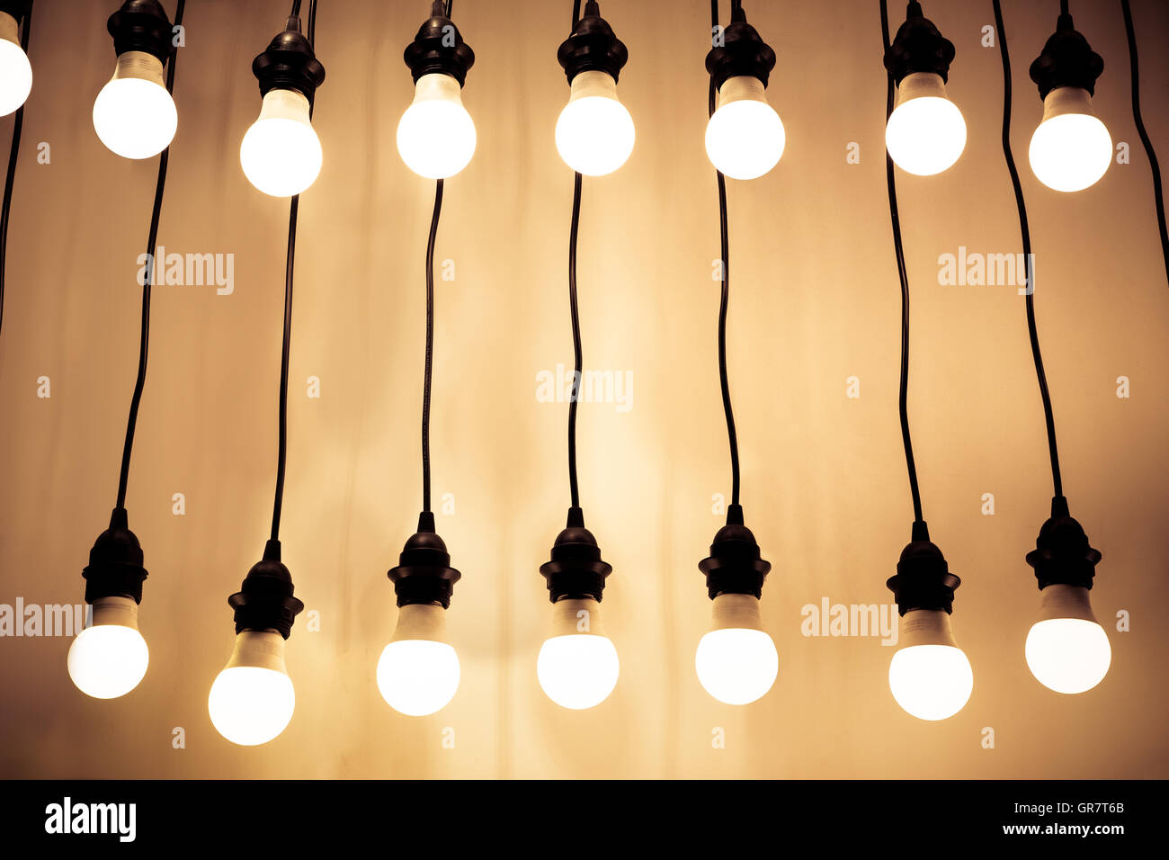 Beleuchteten Glühbirnen hängen Drähte an Wand Stockfoto