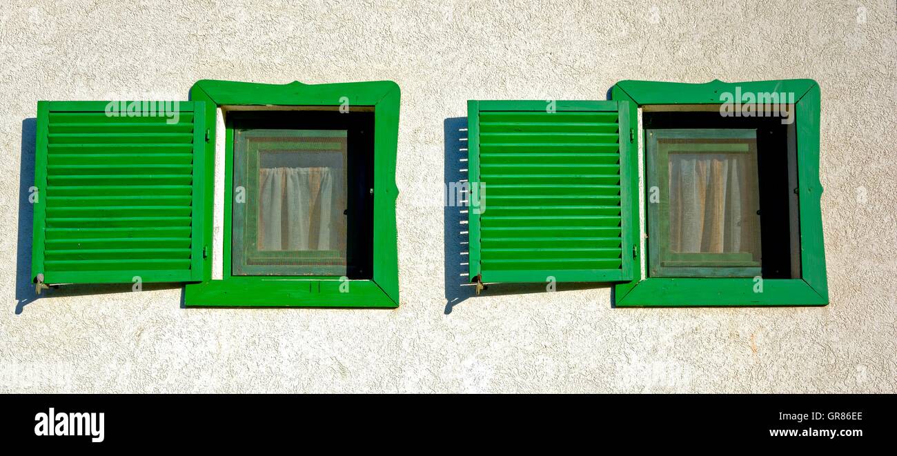 Zwei grüne Holzfenster nebeneinander mit grünen Fensterläden Stockfoto
