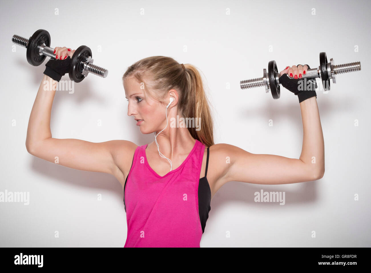 Junge Frau mit einem sportlichen Outfit betreibt seine Krafttraining mit einer Hantel Stockfoto