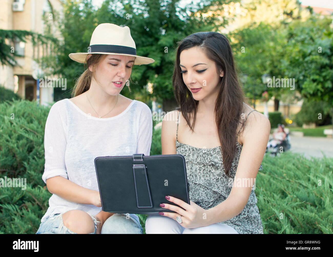 Zwei Freunde betrachten die Tablet-Gerät außerhalb Stockfoto