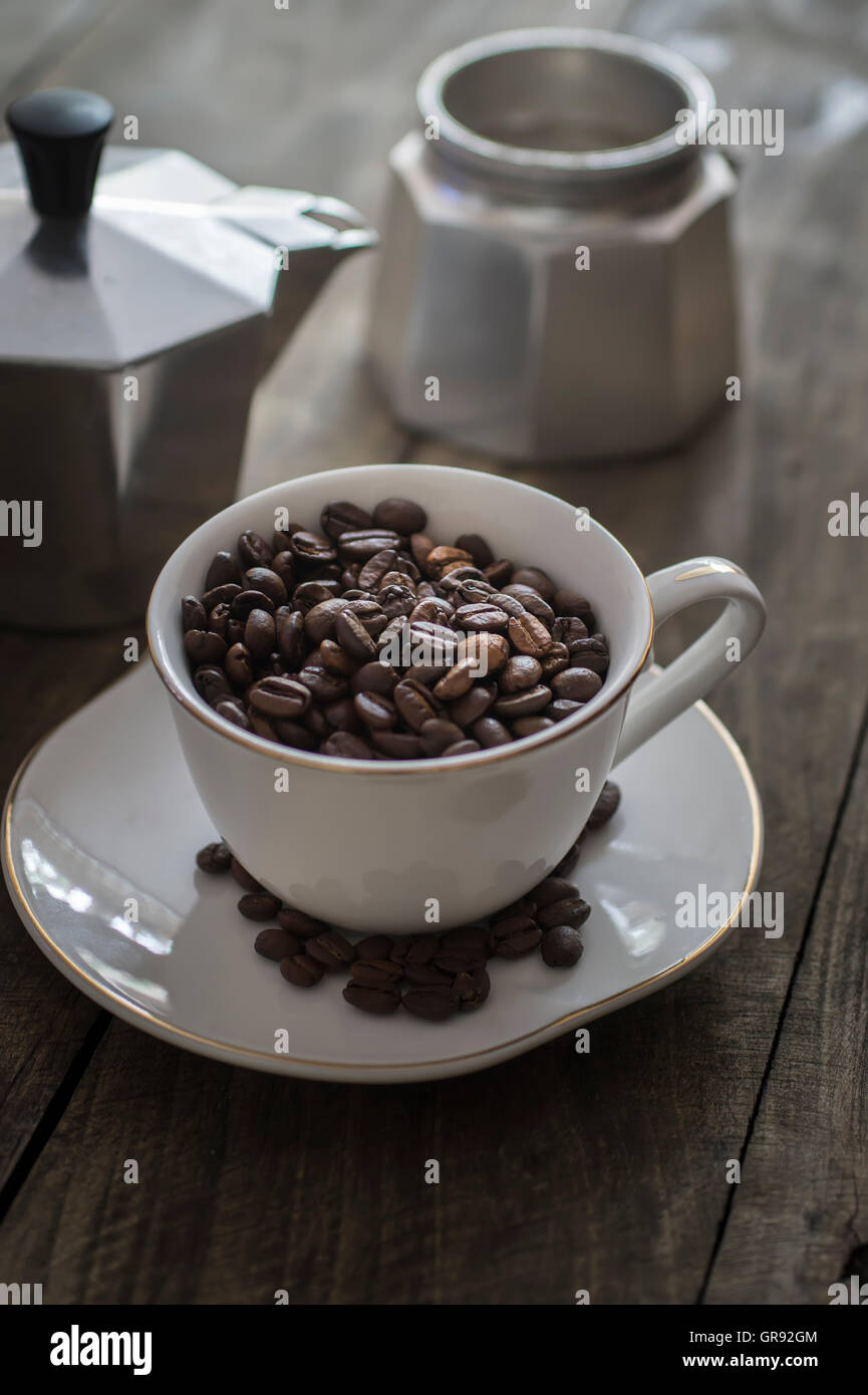 Tasse voll Kaffee Bohnen auf dem hölzernen Hintergrund Stockfoto