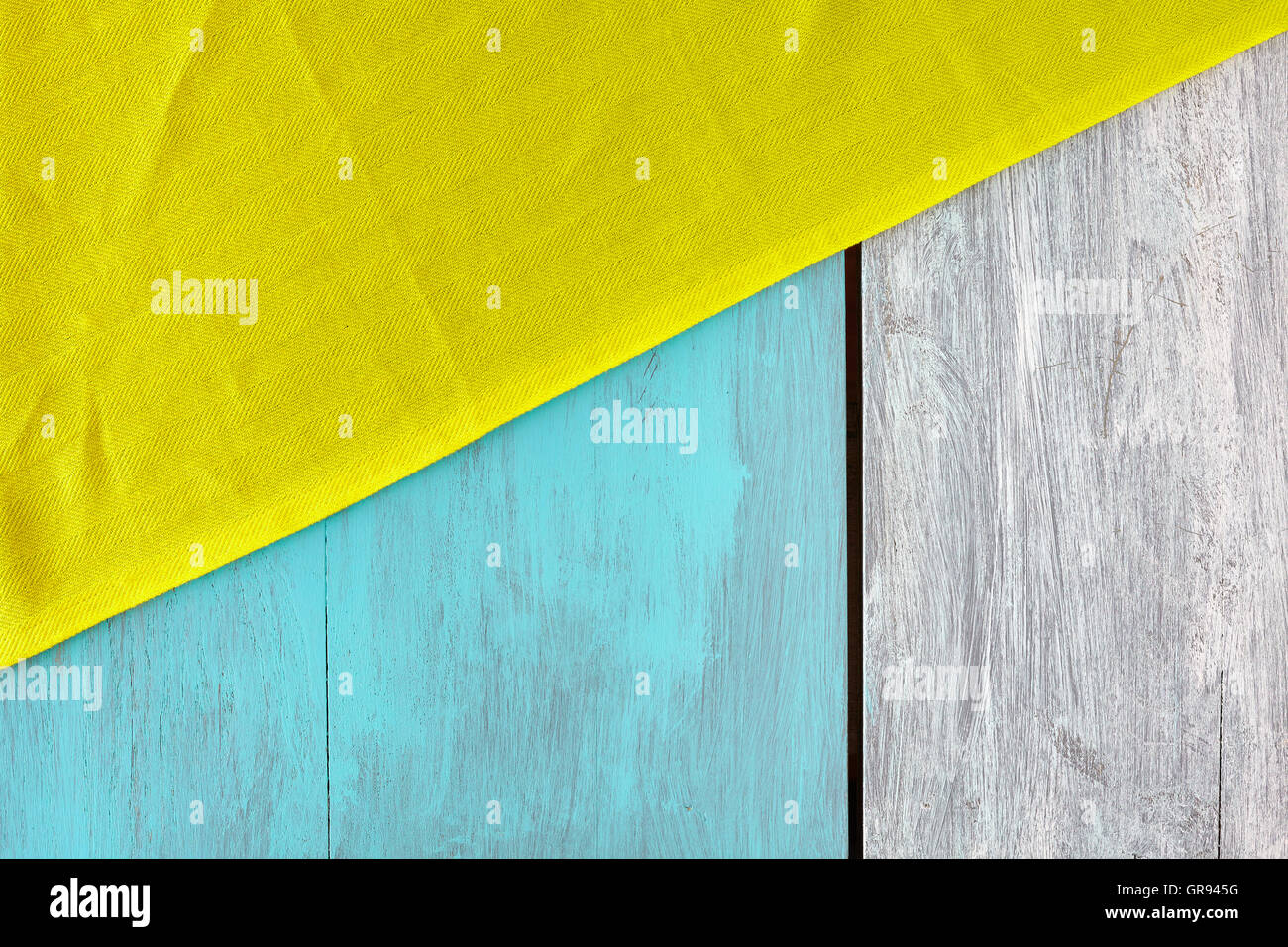 Rustikale blau und weiß lackierten Holztisch mit einer gelben Tischdecke, Ansicht von oben, Textfreiraum. Stockfoto