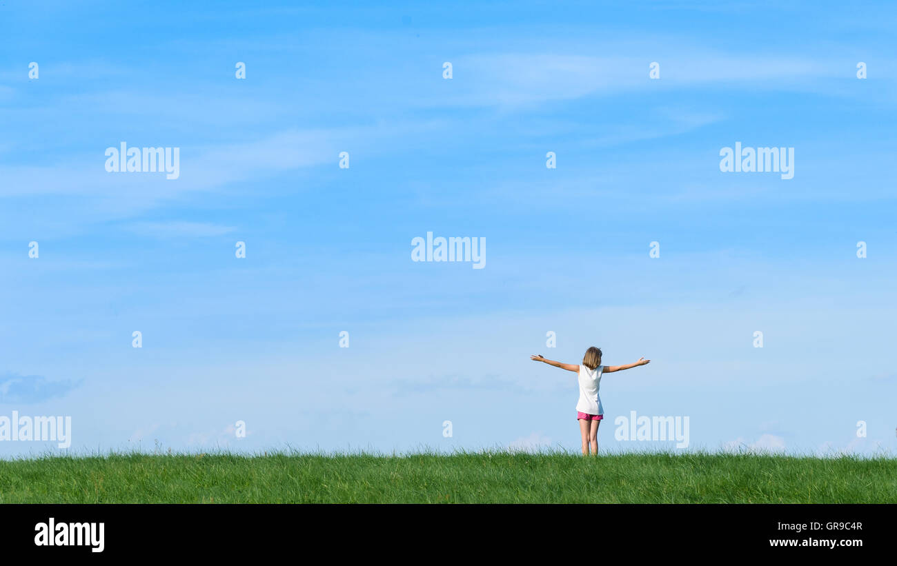 glückliche kleine Mädchen stehen auf einem Berg mit blauem Himmelshintergrund Stockfoto