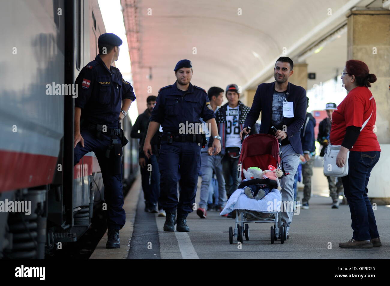 Syrische Flüchtlingsfamilie am Westbahnhof In Wien begleitet von der österreichischen Polizei-Vorstand einen Zug nach Deutschland. Stockfoto