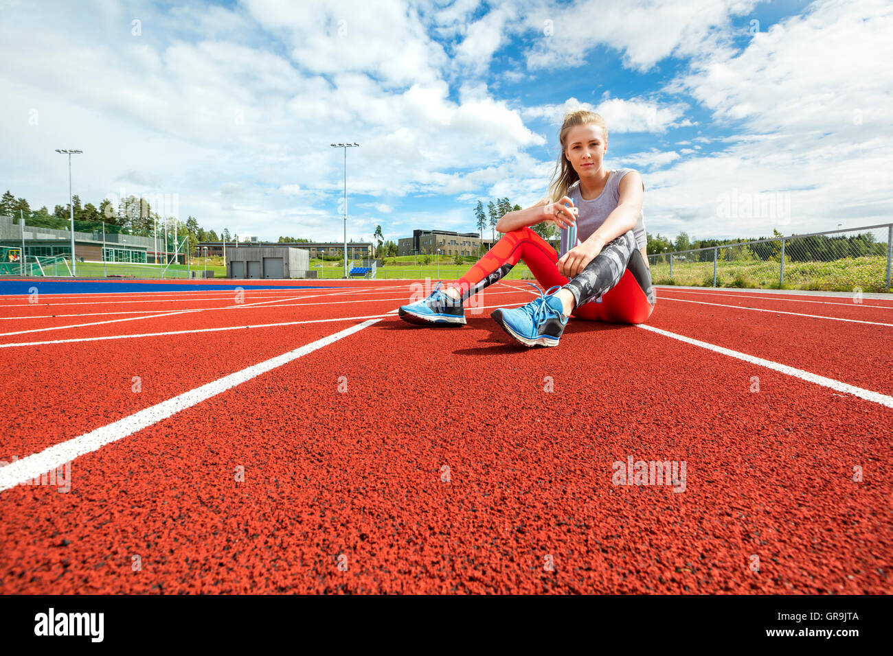 Junge Frau mit Wasserflasche auf Laufstrecken Stockfoto