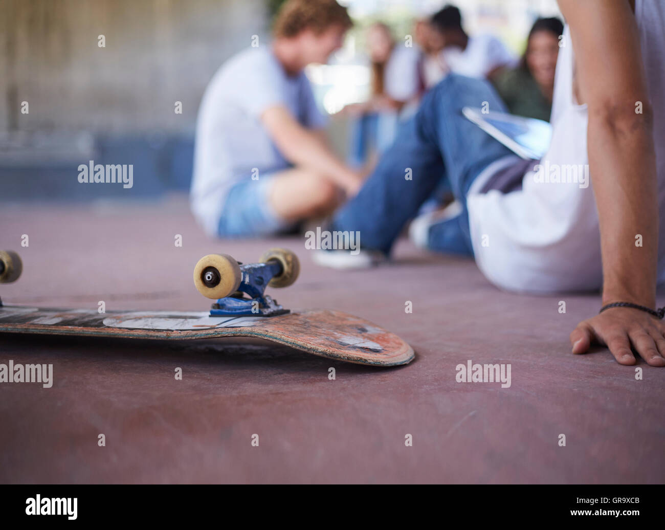 Skateboard kopfüber neben Teenager Freunden abhängen am Skatepark Stockfoto