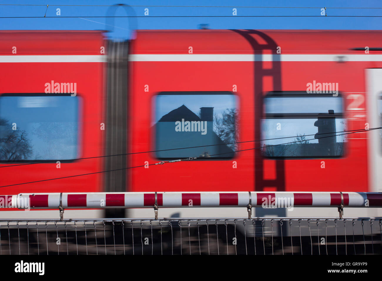 Bahnübergang mit einem vorbeifahrenden Zug Stockfoto