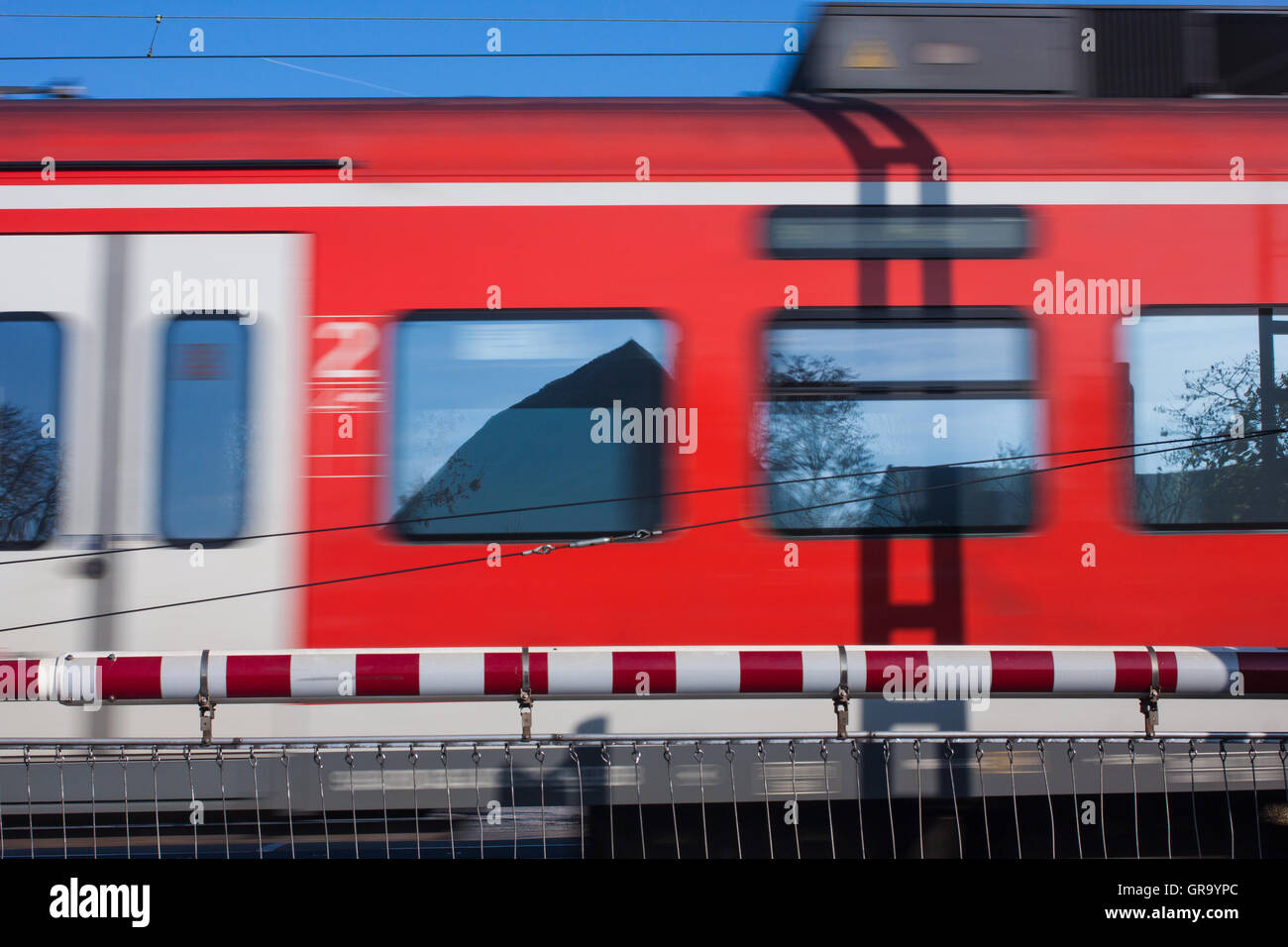 Bahnübergang mit einem vorbeifahrenden Zug Stockfoto