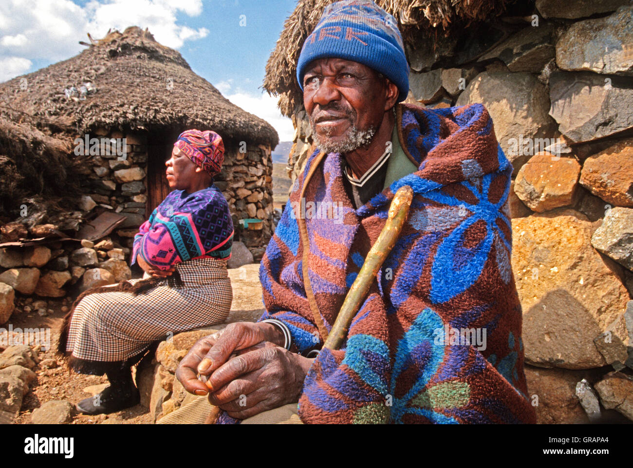 Älteres Ehepaar der Basotho durch ihre Rundhütten in Sani Pass in Lesotho Stockfoto