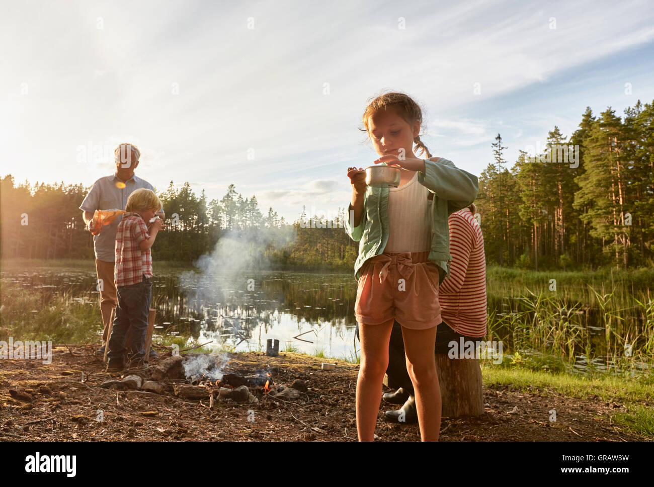 Großeltern und Enkel Kochen am See im Wald Stockfoto