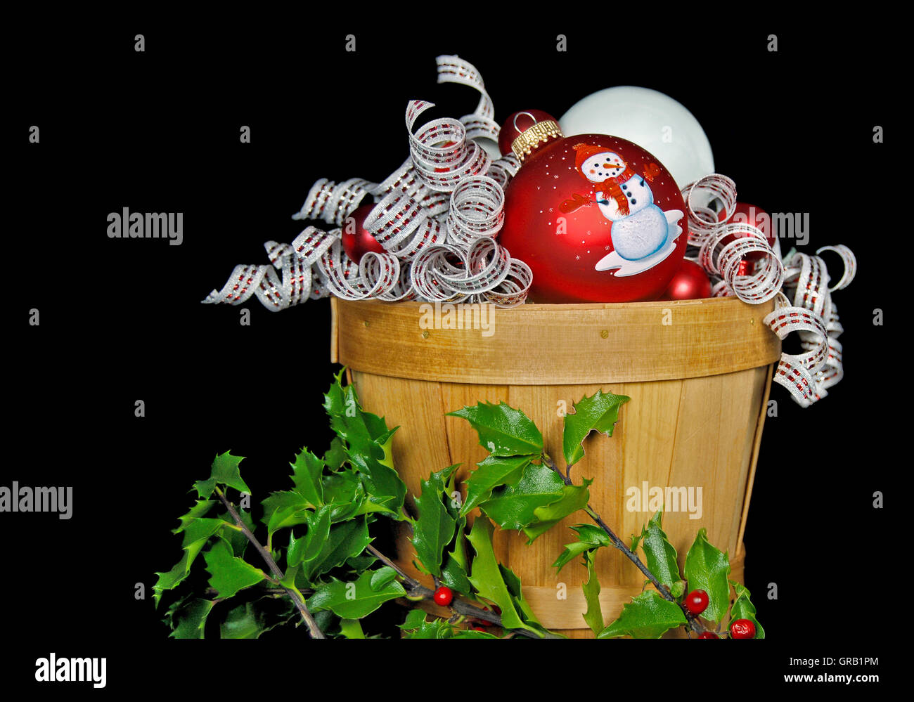 Weihnachtsschmuck und Band in hölzernen Korb mit holly Stockfoto