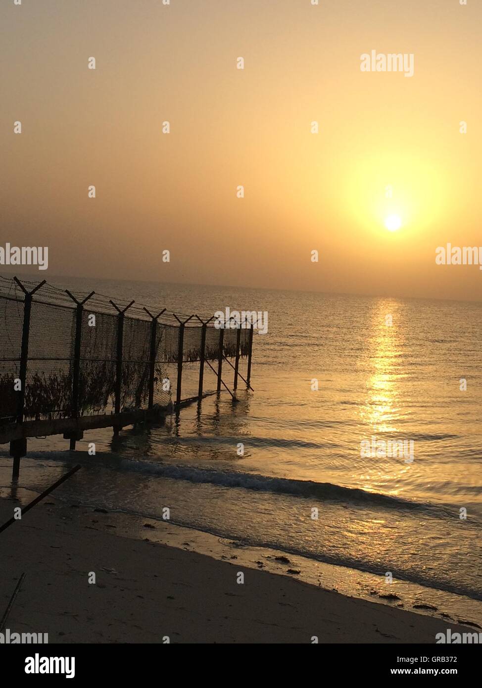 Mitten im Sommer Sonnenaufgang über dem Arabischen Golf mit Zaun Stockfoto