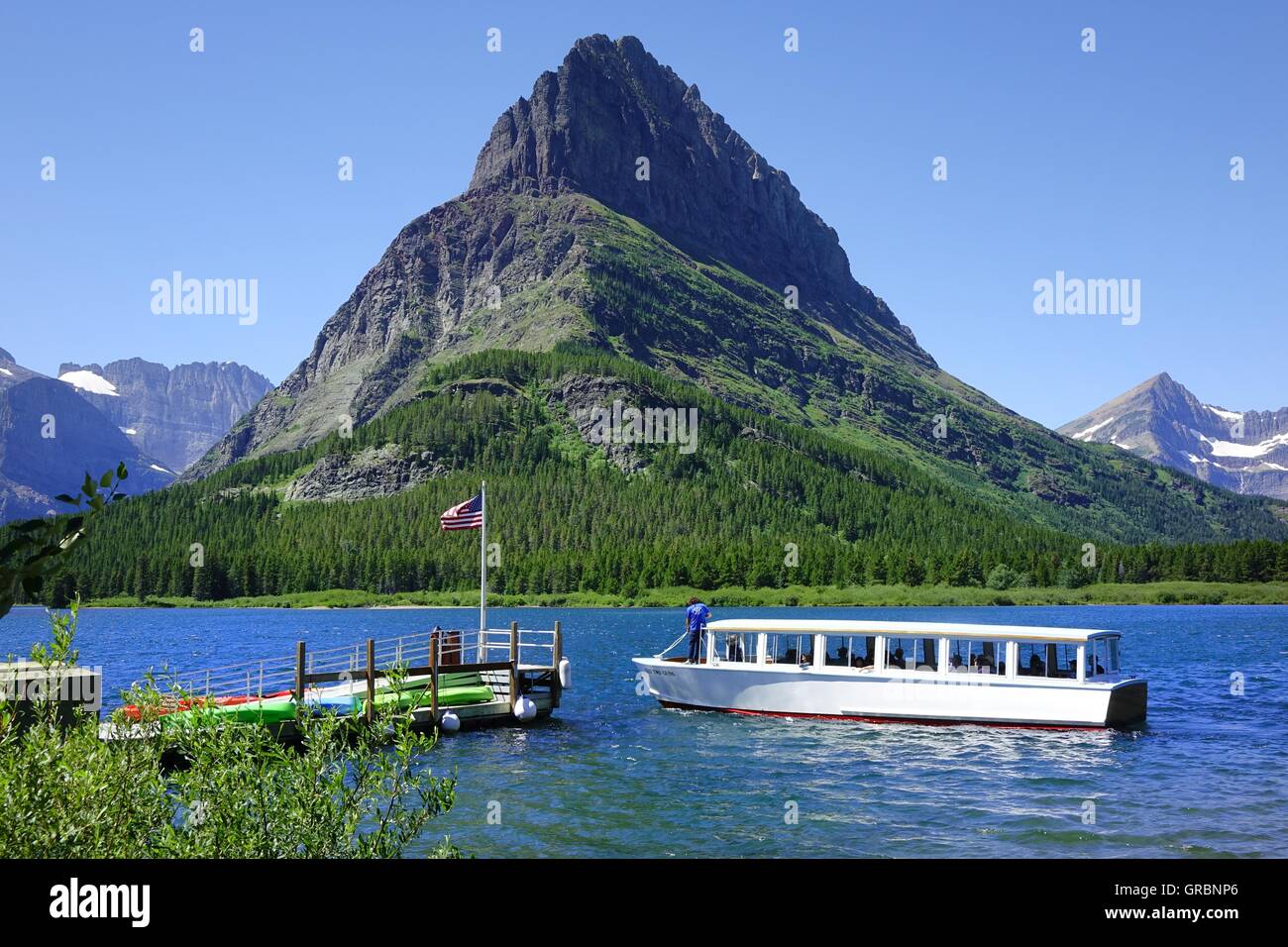 Ausflugsboot nähert sich Dock am Swiftcrrent See, viele Gletschergebiet, Glacier National Park, Montana. Stockfoto