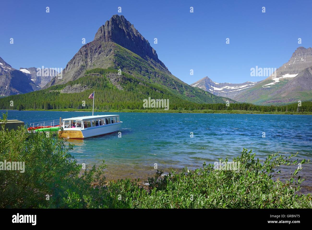 Ausflugsschiff im Dock Masny Glacier Lodge. Grinnell Point ist im Hintergrund, über den See. Glacier Nationalpark, Mont Stockfoto