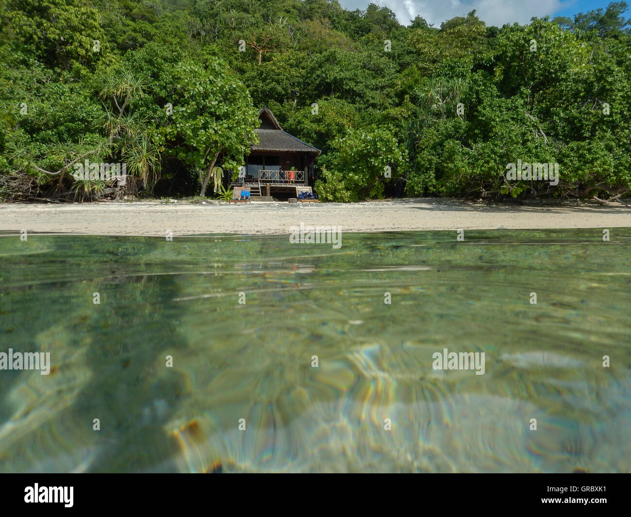 Strand mit weißem Sand, Bungalows im traditionellen Stil, umgeben von tropischer Vegetation, In den Vordergrund-Oberfläche des Wassers. Selayar, Süd-Sulawesi, Indonesien Stockfoto