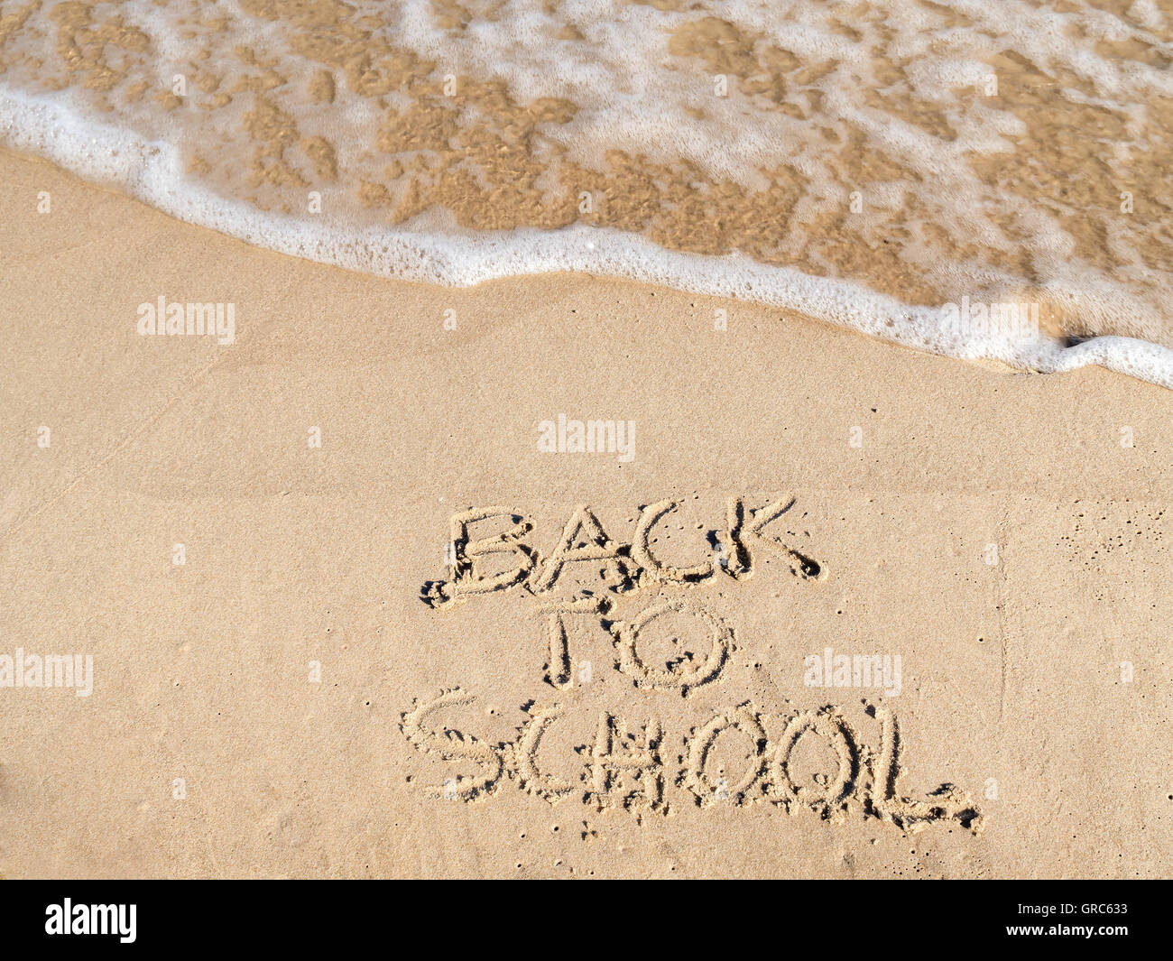 Finger wieder zu Schule schreiben auf Strandsand gezeichnet Stockfoto