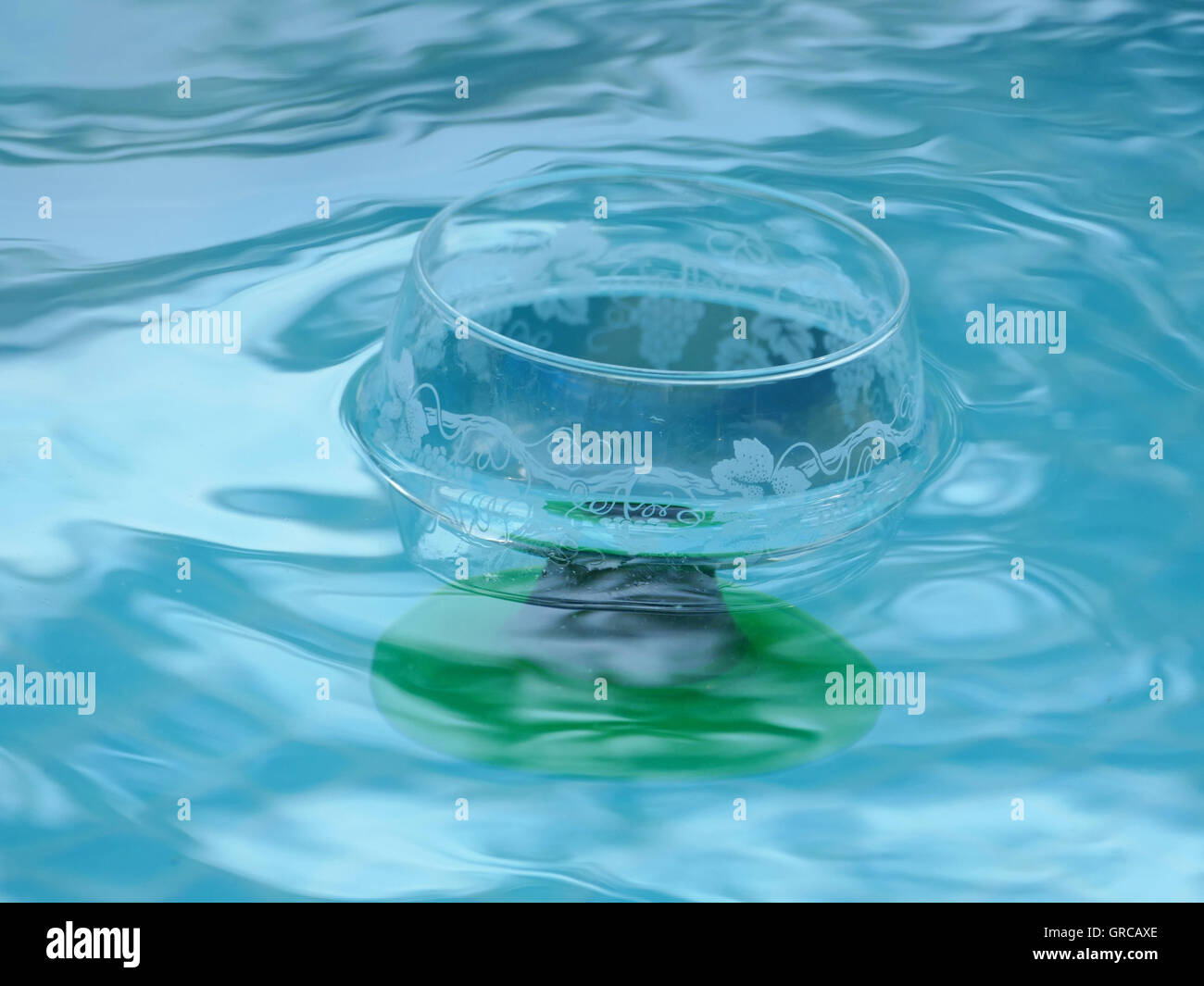 Leere Glas Wein schwimmt auf der Wasseroberfläche aus einem Pool, Pool-Party Stockfoto